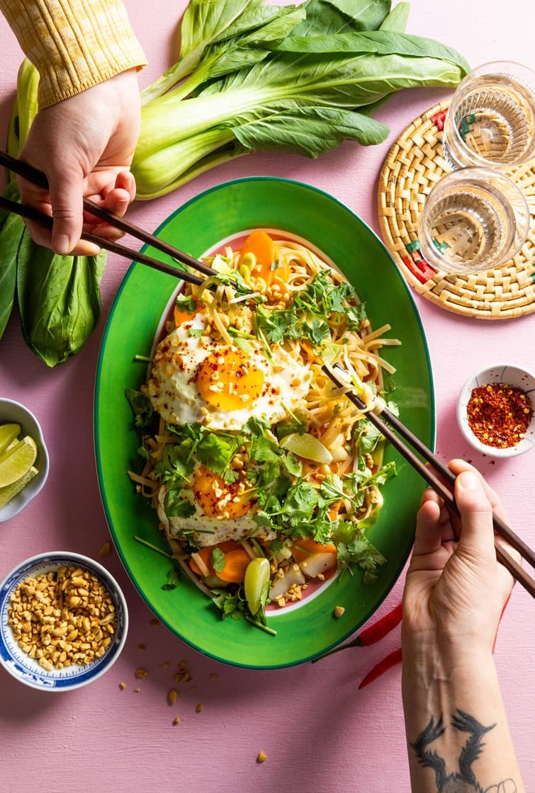 Thaimaalainen nuudeliwokki chilillä paistetulla kananmunalla, pak choi, pavunidut, korianteri ja maapähkinät