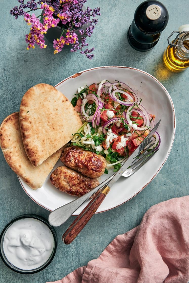 Italialainen salsicciakebab pitaleivässä sitruunalla maustetun kaalin, tomaatin ja persiljan kanssa